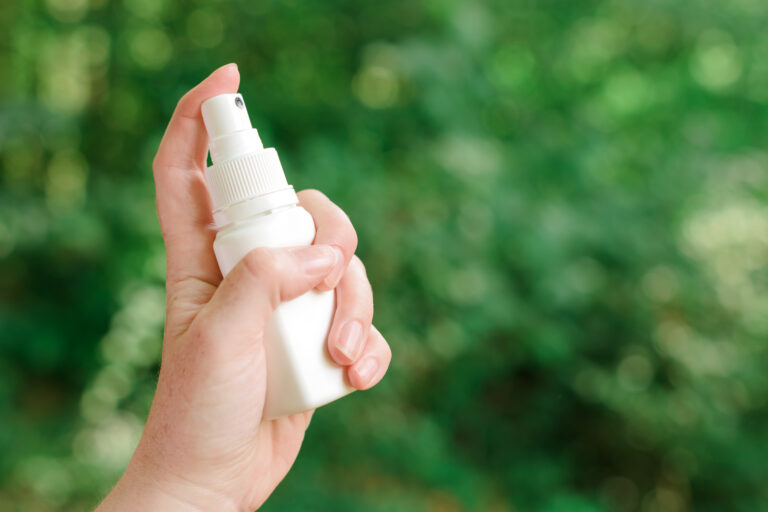 Woman using antiseptic spray outdoors in forest to protect the injury wound from infection, selective focus
